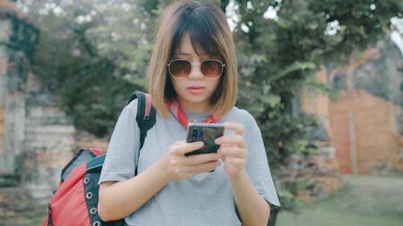 Traveler Asian woman using smartphone for direction and looking on location map while spending holiday trip at Ayutthaya, Thailand, backpacker female enjoy journey in traditional city.の写真素材