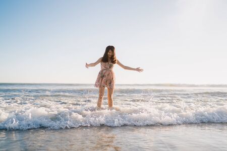 Young Asian woman walking on beach. Beautiful female happy relax walking on beach near sea when sunset in evening. Lifestyle women travel on beach concept.の写真素材