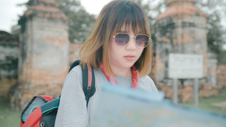 Traveler Asian woman direction and looking on location map while spending holiday trip at Ayutthaya, Thailand, backpacker female enjoy journey in traditional city. Lifestyle women travel concept.の写真素材