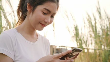 Cheerful Asian tourist blogger woman using smartphone for direction and looking on location map while traveling on the street at downtown city. Lifestyle backpack tourist travel holiday concept.の写真素材