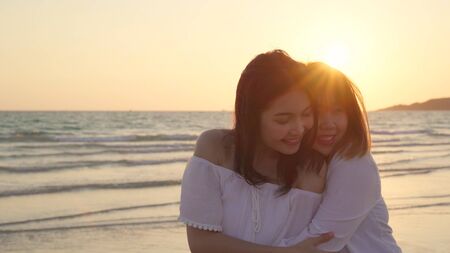 Young Asian lesbian couple kissing near beach. Beautiful women lgbt couple happy relax enjoy love and romantic moment when sunset in evening. Lifestyle lesbian couple travel on beach concept.の写真素材