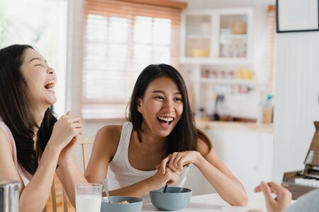 Asian women have breakfast at home, Group of young Asia friend girls feeling happy fun talking together while have breakfast in kitchen in the morning concept.の写真素材