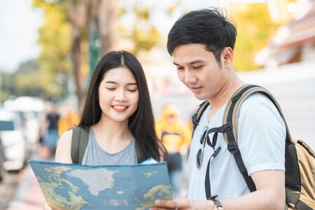 Traveler Asian couple direction on location map in Bangkok, Thailand, sweet Asia couple looking on map find landmark while spending holiday trip. Lifestyle couple travel in city concept.の写真素材