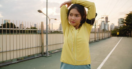 Beautiful young Asia athlete lady exercises using smartphone for listen to music while running in...