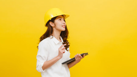 Young Asian woman engineer using digital tablet with positive expression, dressed in casual clothing...