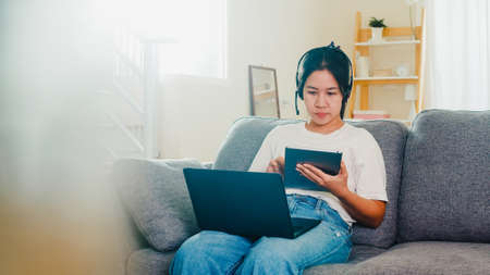 Asian freelance business woman casual wear using laptop working call video conference with customer in workplace in living room from home when social distancing stay at home and self quarantine time.の写真素材
