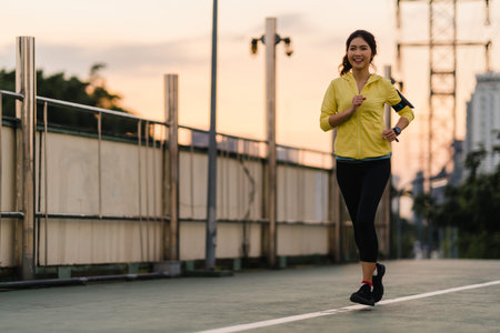 Beautiful young Asia athlete lady running exercises work out in urban environment. Japanese teen...