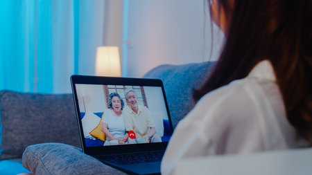 Asia student exchange female using laptop video call talking with family while working from home at...