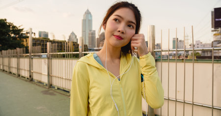 Beautiful young Asia athlete lady exercises using smartphone for listen to music while running in...