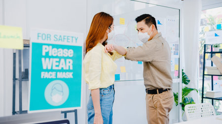 Asia businesspeople greeting with elbow bump and wear medical face mask for social distancing in new...