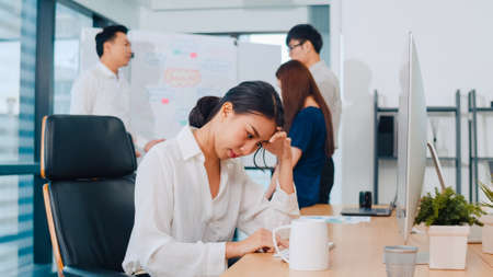 Millennial young businesswoman working stress out with project research problem on computer desktop in meeting room at small modern office. Asia people occupational burnout syndrome concept.の写真素材