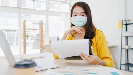 Asia businesswoman entrepreneur wearing medical face mask for social distancing in new normal...