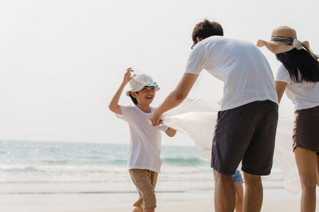 Asian young happy family activists collecting plastic waste on beach. Asia volunteers help to keep nature clean up and pick up garbage. Concept about environmental conservation pollution problems.の写真素材