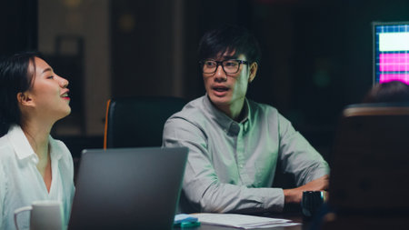 Asia businessmen and businesswomen meeting brainstorming ideas conducting business presentation project colleagues working together plan success strategy enjoy teamwork in small modern night office.の写真素材