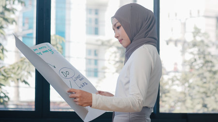 Asia muslim lady drawing work plan think information reminder on paper in new normal office. Working from home, remotely work, self isolation, social distancing, quarantine for coronavirus prevention.の写真素材