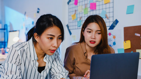Group of Asia businesspeople using computer laptop presentation and communication meeting brainstorming ideas about new project colleagues working plan success strategy in night modern home office.の写真素材