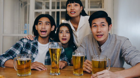 Group of tourist young Asia friend watching football in sports TV, drink alcohol beer and having hangout party in night club at Khao San Road. Traveler backpacker people travel in Bangkok, Thailand.の写真素材