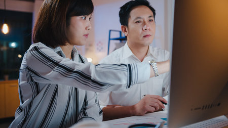 Group of Asia businessman and businesswoman using computer presentation and communication meeting brainstorming ideas about new project colleagues working plan success strategy in night home office.の写真素材