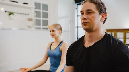 Young American couple in sportswear doing yoga exercise working out in kitchen at home at morning....