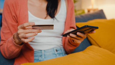 lady use cellphone order online shopping product with credit card on sofa in living room.