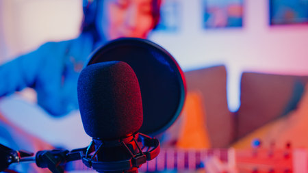 Happy asia girl blogger play guitar and use microphone sing song record music sound mixer on laptop...