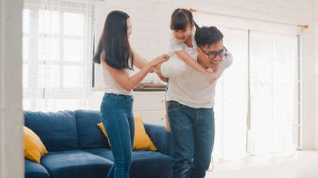 Happy cheerful Asian family dad, mom and daughter having fun playing congratulations with birthday at at house.の写真素材