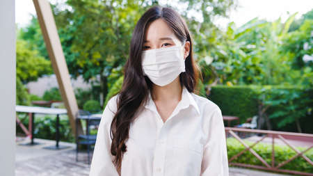 Young Asia businesswoman wear protective face mask looking at cameraの写真素材