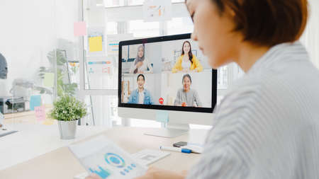 Asia business people using desktop talk to colleagues discussing business brainstorm about plan in video call meeting in new normal office.の写真素材