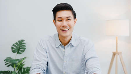 Portrait of successful handsome executive businessman smart casual wear looking at camera and smiling, happy in modern office workplace. Young Asia guy talk to colleague in video call meeting at home.の写真素材
