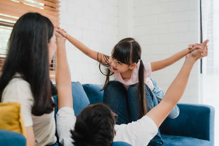 Happy cheerful Asian family dad, mom and daughter having fun playing congratulations with birthday at at house. Self-isolation, stay at home, social distancing, quarantine for  virus prevention.の写真素材