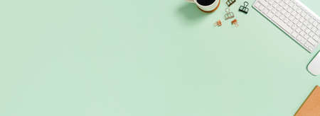 Creative flat lay photo of workspace desk. Top view office desk with keyboard and mouse on pastel green color background. Panoramic banner with copy space for text and Advertising area.の写真素材