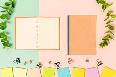 Creative flat lay photo of workspace desk. Top view office desk with adhesive note and open mockup black notebook on pastel green pink color background. Top view mock up with copy space photography.の写真素材