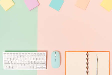 Creative flat lay photo of workspace desk. Top view office desk with keyboard, mouse and open mockup black notebook on pastel green pink color background. Top view mock up with copy space photography.の写真素材