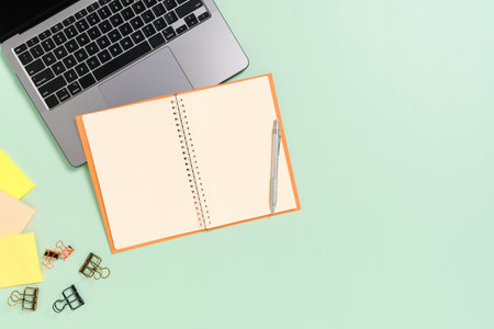 Creative flat lay photo of workspace desk. Top view office desk with laptop, coffee cup and open mockup black notebook on pastel green color background. Top view mock up with copy space photography.の写真素材