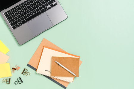 Creative flat lay photo of workspace desk. Top view office desk with laptop, coffee cup and open mockup black notebook on pastel green color background. Top view mock up with copy space photography.の写真素材