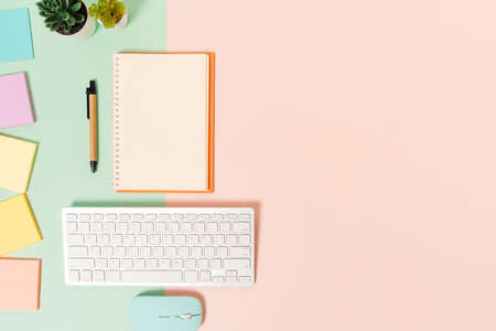Creative flat lay photo of workspace desk. Top view office desk with keyboard, mouse and open mockup black notebook on pastel green pink color background. Top view mock up with copy space photography.の写真素材