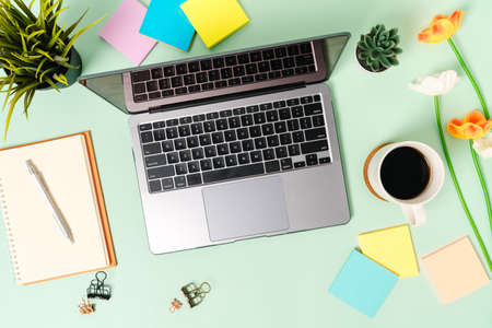 Creative flat lay photo of workspace desk. Top view office desk with laptop, coffee cup and open mockup black notebook on pastel green color background. Top view mock up with copy space photography.の写真素材
