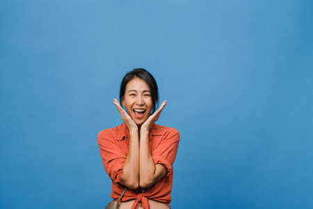 Young Asia lady with positive expression, smile broadly, dressed in casual clothing and looking at camera over blue background. Happy adorable glad woman rejoices success. Facial expression concept.の写真素材