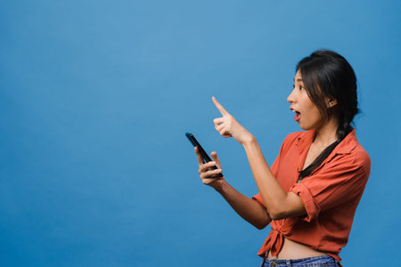 Portrait of young Asian lady using mobile phone with cheerful expression, show something amazing at...