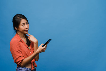 Young Asia lady using phone with positive expression, smiles broadly, dressed in casual clothing...