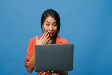 Young Asia lady using laptop with positive expression, smiles broadly, dressed in casual clothing...