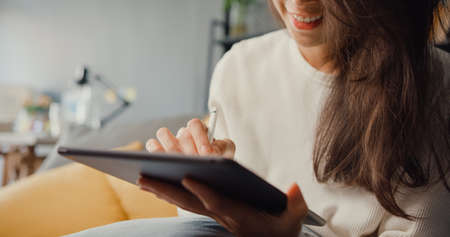 Close up freelance Asia lady casual wear using tablet online learn in living room at house.の写真素材