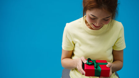 Young Asia girl smile and receiving present box isolated over blue background. Copy space for place...