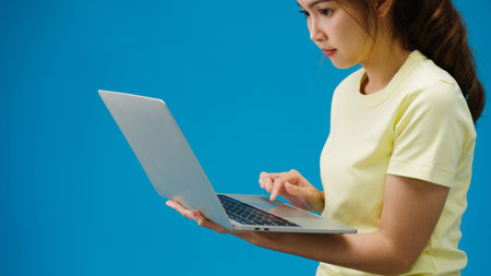 Young girl shopping online with laptop and payment order online isolated over blue background. Copy...