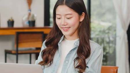 Cheerful Young Asian freelance lady working on laptop at coffee shop. Attractive Japanese businesswoman relax feeling happy in urban cafe or restaurant.の写真素材
