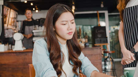 Young Asia freelance lady client talk dispute with millennial waitress feel dissatisfied with cafe bad service, mad disappointed customers speak with staff complain about wrong order coffee shop.の写真素材