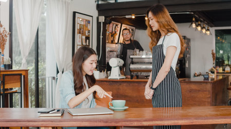 Young Asia freelance lady client talk dispute with millennial waitress feel dissatisfied with cafe bad service, mad disappointed customers speak with staff complain about wrong order coffee shop.の写真素材