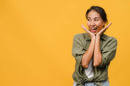 Portrait of young Asia lady with positive expression, smile broadly, dressed in casual clothing over yellow background. Happy adorable glad woman rejoices success. Facial expression concept.の写真素材