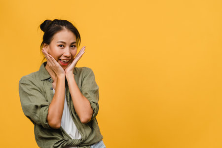 Young Asia lady with positive expression, smile broadly, dressed in casual clothing and looking at camera over yellow background. Happy adorable glad woman rejoices success. Facial expression concept.の写真素材