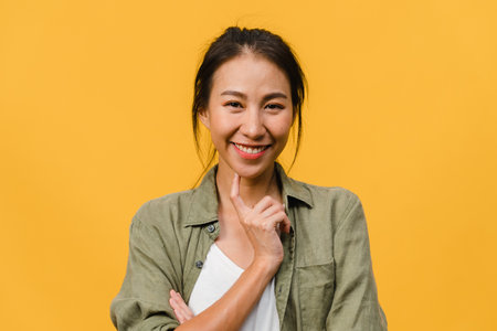 Young Asia lady with positive expression, smile broadly, dressed in casual clothing and looking at camera over yellow background. Happy adorable glad woman rejoices success. Facial expression concept.の写真素材